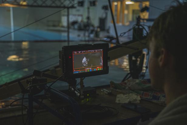 Ein Mann beobachtet einen Monitor mit einer Aufnahme während Dreharbeiten.