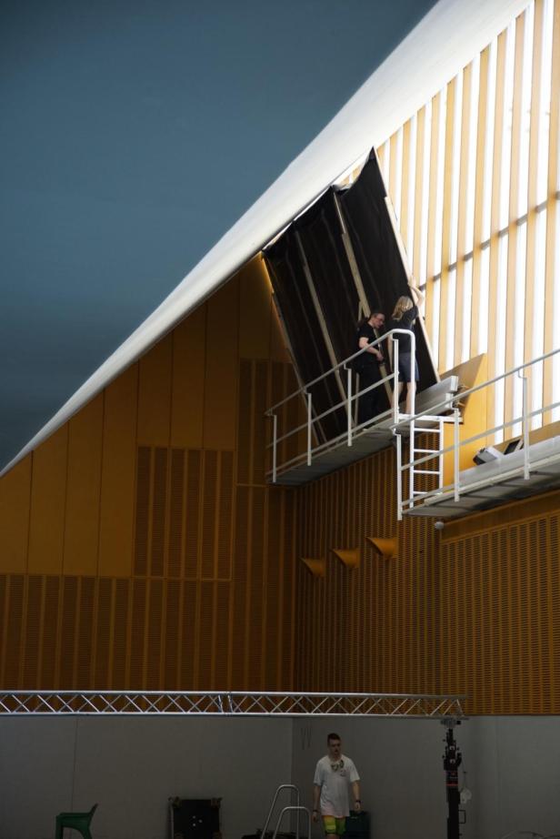 Zwei Personen arbeiten an einer Bühnenkonstruktion in einer Halle.