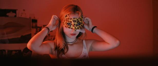 Eine junge Frau setzt eine Leopardenmaske auf.