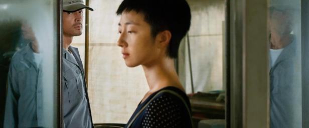 Ein Mann mit Kappe und ein junger Mensch stehen in einem Raum.