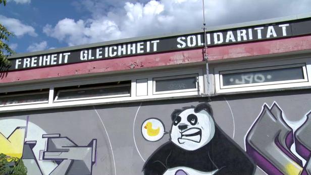 Ein Gebäude mit Graffiti, darunter ein Panda mit einer Sprechblase mit einer Ente, und der Aufschrift „Freiheit Gleichheit Solidarität“.