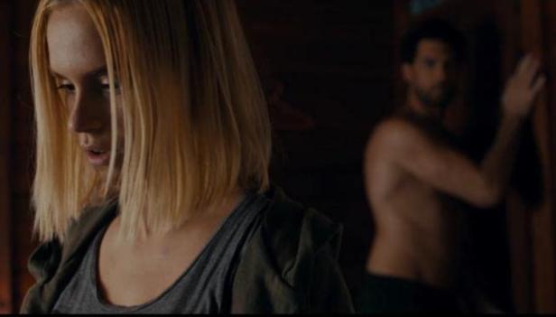 Eine blonde Frau im Vordergrund, im Hintergrund ein Mann ohne Hemd.