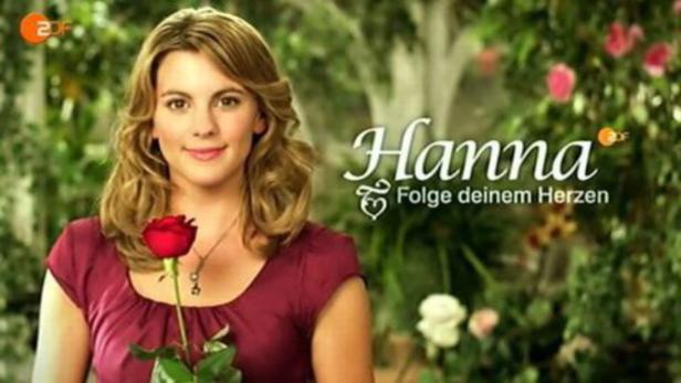 Eine lächelnde Frau hält eine rote Rose in der Hand, im Hintergrund der Schriftzug „Hanna“.