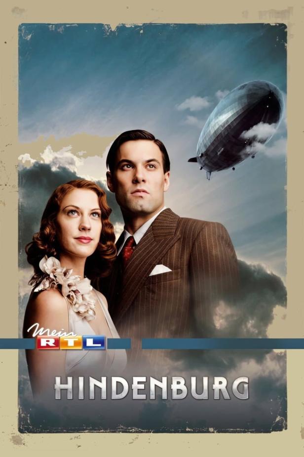 Ein Filmposter für „Hindenburg“ mit einem Paar und einem Luftschiff im Hintergrund.