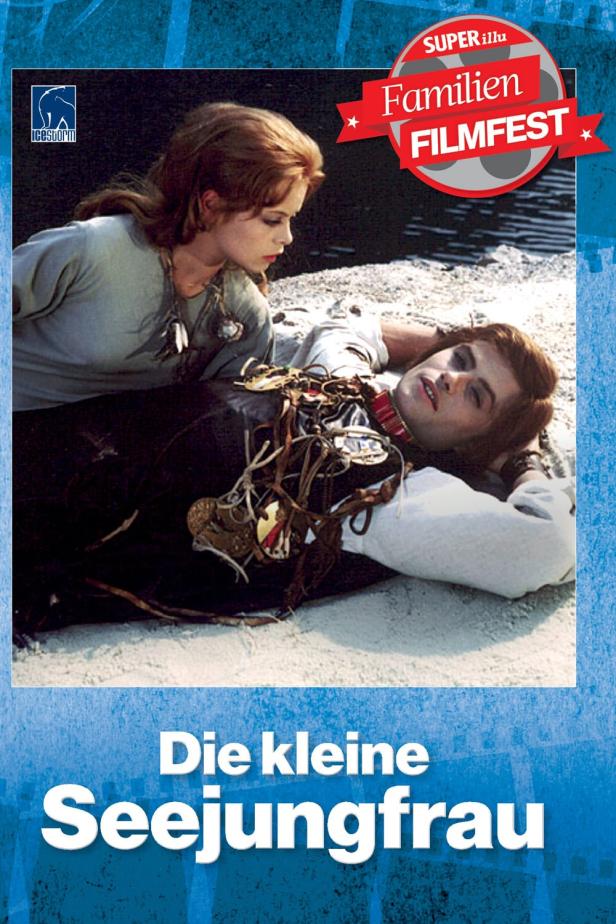 Eine Frau beugt sich über einen Mann, der mit Schmuck behangen am Strand liegt.