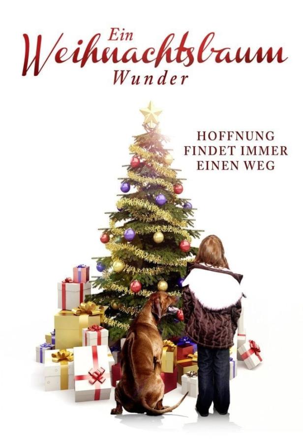 Ein Mädchen und ein Hund stehen vor einem Weihnachtsbaum mit Geschenken.