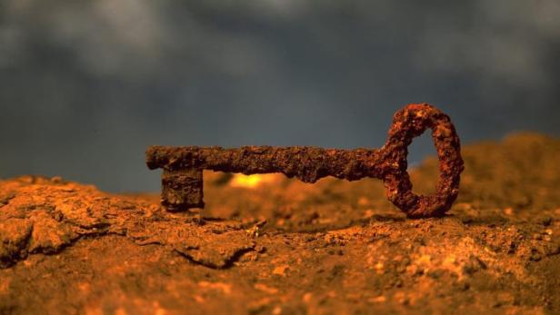 Ein verrosteter Schlüssel liegt auf einer ebenfalls verrosteten Oberfläche.