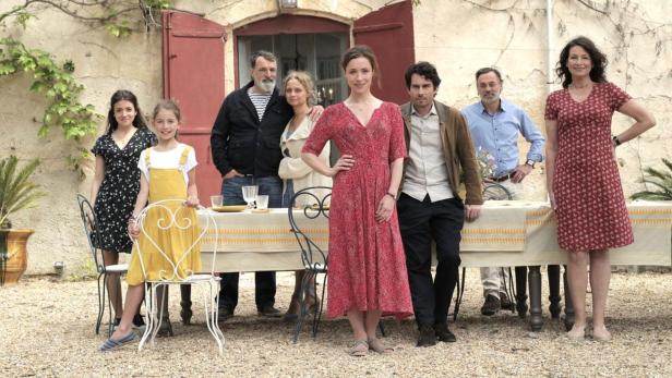 Eine Gruppe von Menschen steht vor einem gedeckten Tisch im Freien.