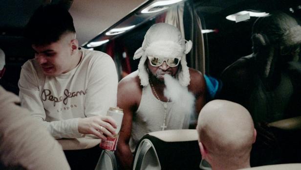 In einem Bus raucht ein Mann mit Mütze und Sonnenbrille eine E-Zigarette.