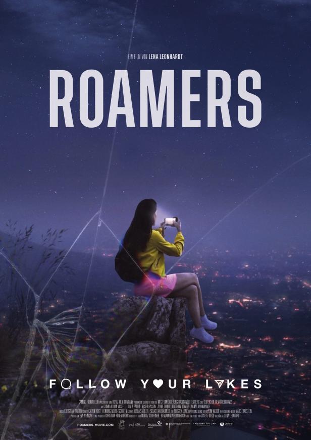 Plakat für den Film „Roamers“: Eine junge Frau fotografiert die nächtliche Stadt unter einem Sternenhimmel.