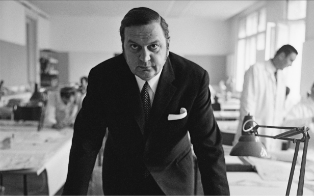 Ein Mann im Anzug steht in einem Büro mit Schreibtischlampen.