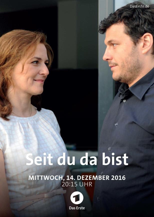 Eine Frau und ein Mann schauen sich an; Filmposter „Seit du da bist“.