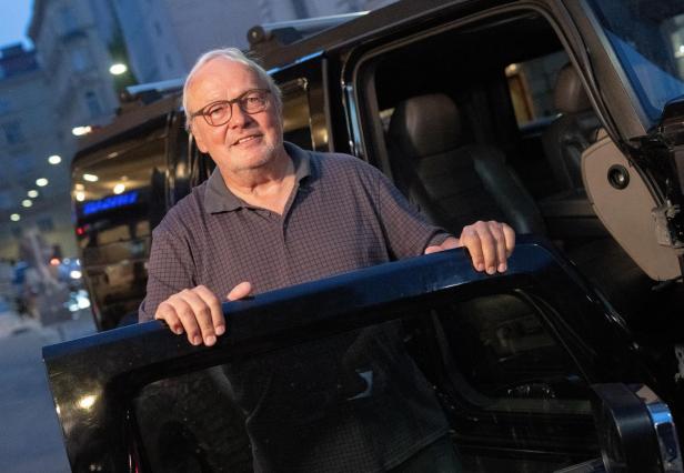 Ein älterer Mann mit Brille steigt aus einem schwarzen Geländewagen.