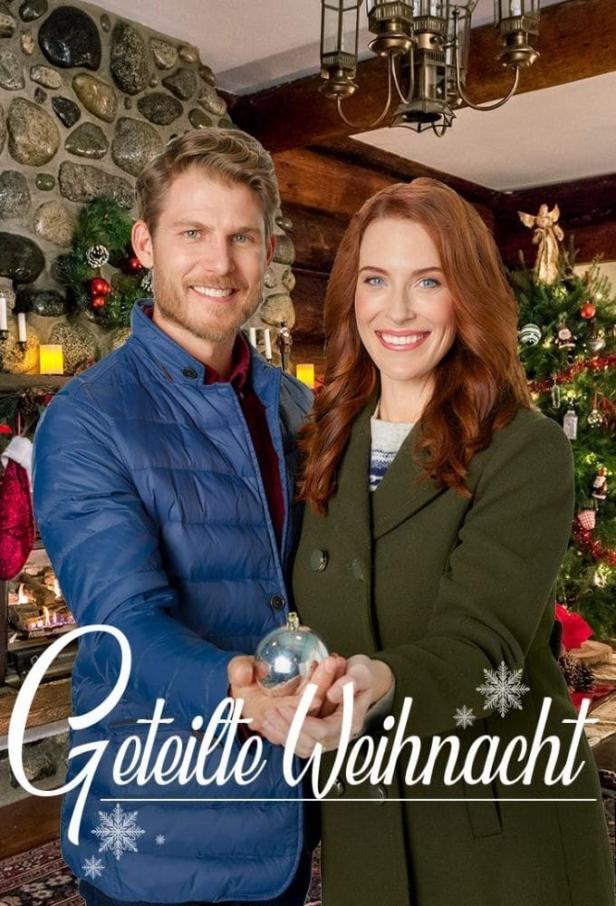 Ein Mann und eine Frau halten eine Christbaumkugel vor einem Weihnachtsbaum.