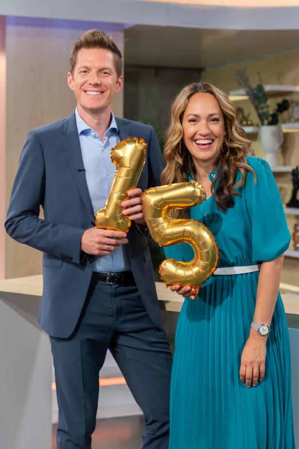 Zwei Personen halten goldene Ballons in Form der Zahl 15.