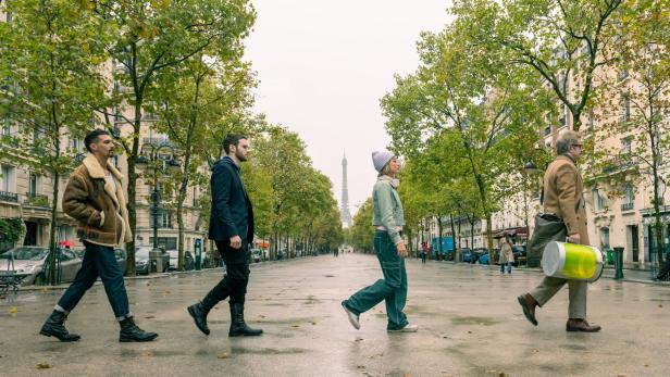 Vier Menschen laufen über eine Straße in Paris. 