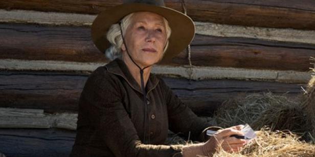 Helen Mirren vor einer Holzhütte mit einem Hut