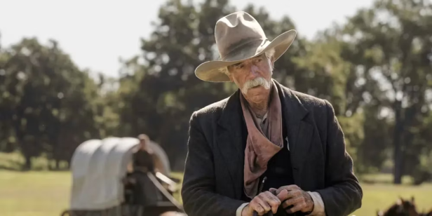 Ein alter Cowboy mit Schnurrbart steht vor einem Planwagen