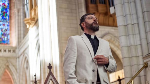 Ein Priester steht in einer Kirche und blickt nach oben.