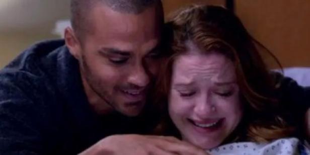 Jackson und April lächeln auf ihr Baby nieder, das man im Bild nicht sieht. Sie weint und trägt Krankenhaus-Kleidung.