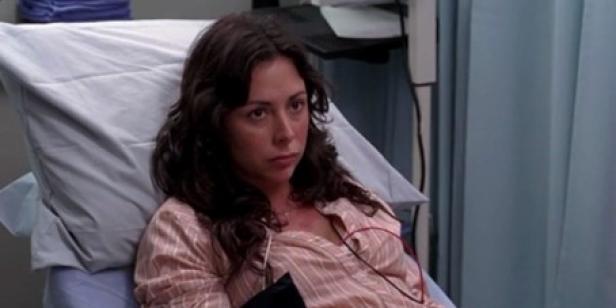 Eine Frau mit braunen, mittellangen Haaren im jungen Alter liegt in einem Krankenhausbett.