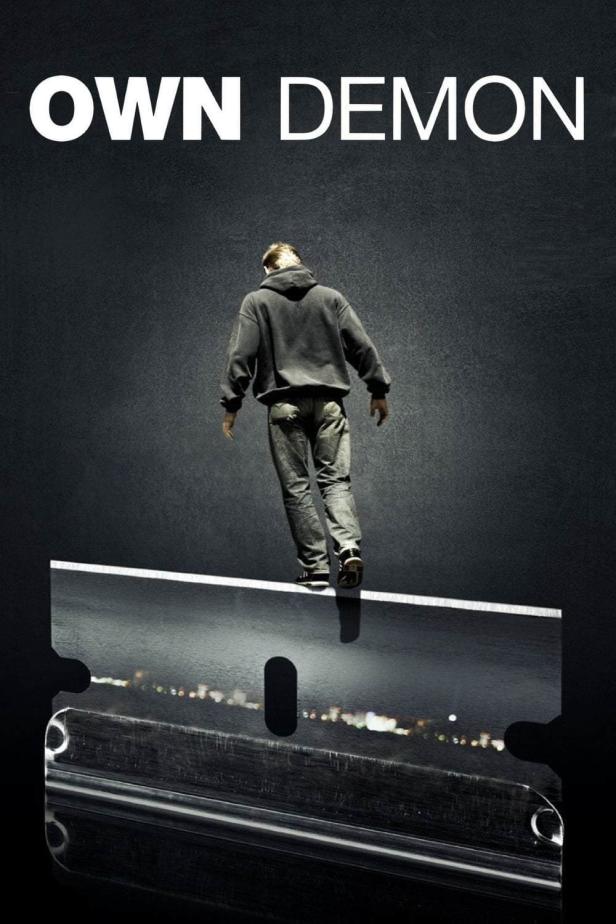 Ein Mann balanciert auf einer Rasierklinge; im Hintergrund der Titel „Own Demon“.