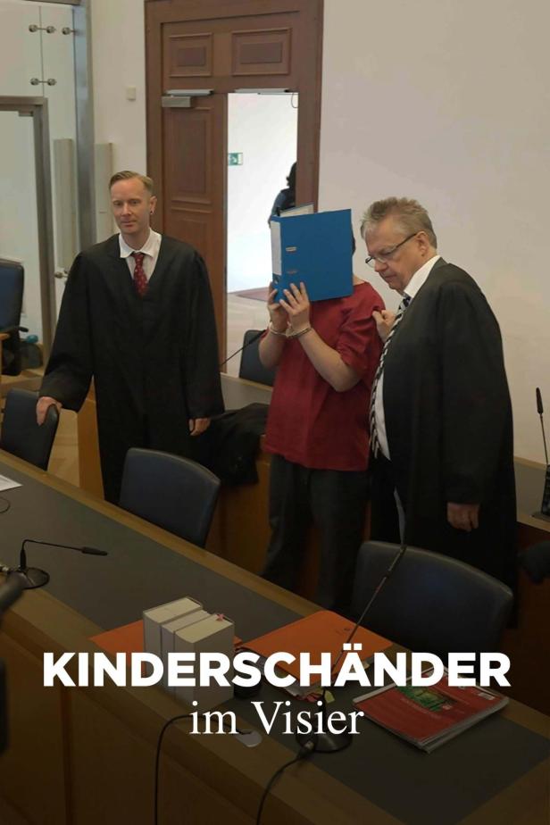 Ein Angeklagter mit Handschellen versteckt sein Gesicht hinter einer Akte im Gerichtssaal.