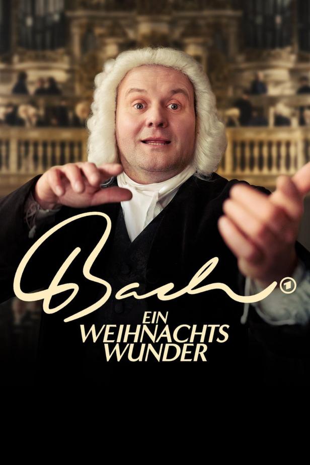 Ein Mann in historischer Kleidung und Perücke vor dem Hintergrund des Films „Bach – Ein Weihnachtswunder“.