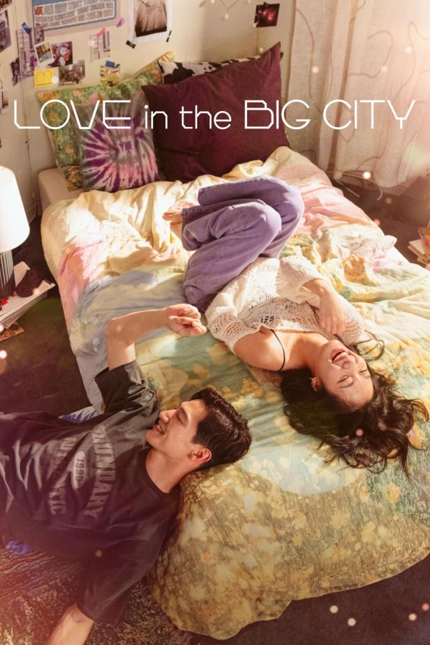 Ein Mann und eine Frau liegen lachend auf einem Bett unter dem Titel „Love in the Big City“.