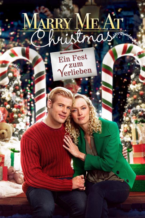 Das Filmplakat für „Marry Me at Christmas: Ein Fest zum Verlieben“ zeigt ein Paar vor weihnachtlicher Kulisse.