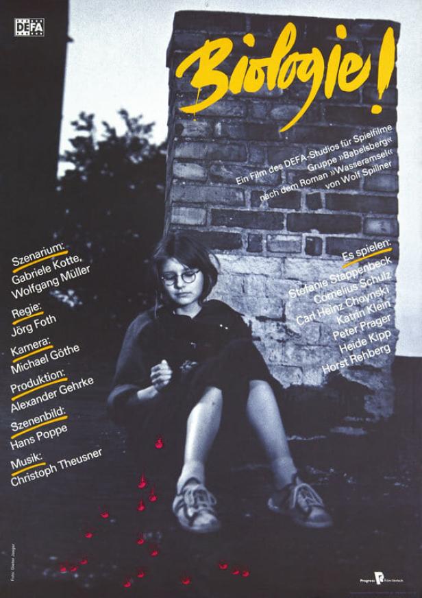 Filmplakat für „Biologie!“ mit einer jungen Frau vor einer Backsteinmauer.