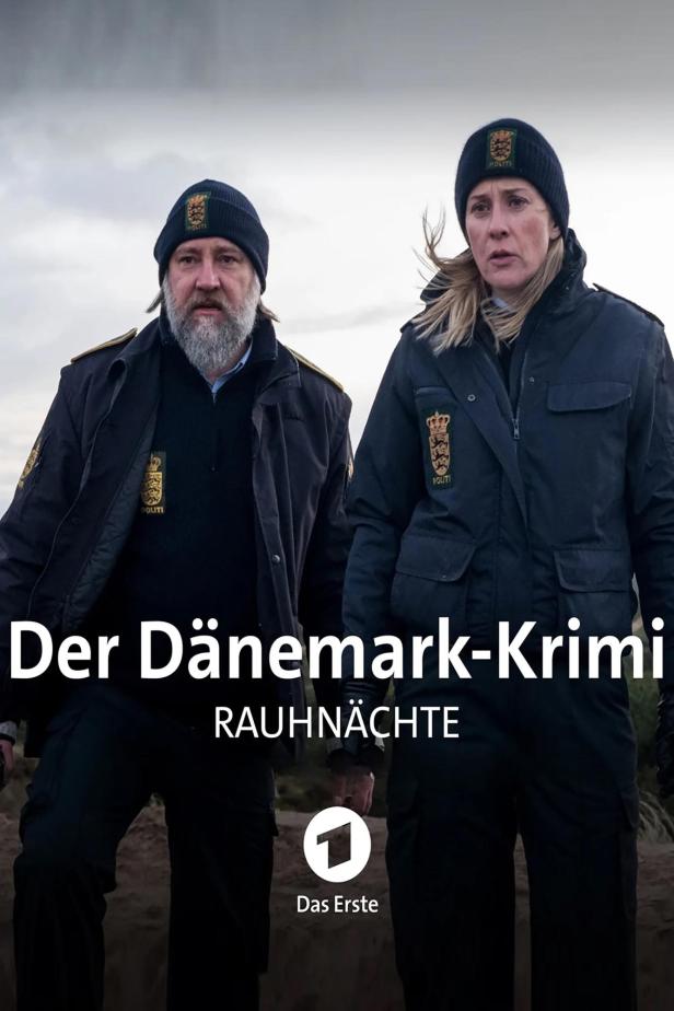 Zwei dänische Polizisten in Uniform stehen vor einer trüben Landschaft.