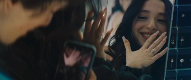 Eine Frau betrachtet ihren neuen Verlobungsring in einem Schmuckgeschäft.