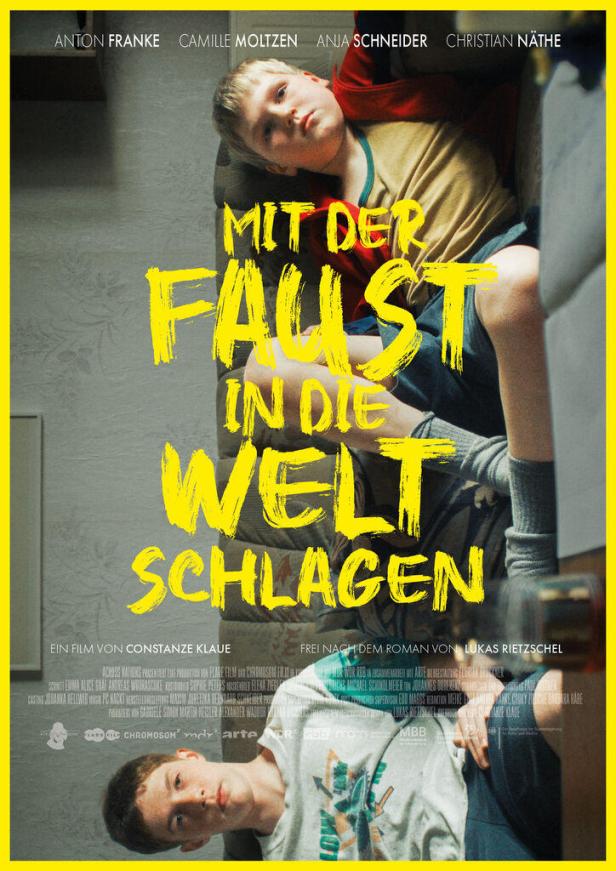 Das Filmplakat für „Mit der Faust in die Welt schlagen“ zeigt zwei Jungen auf einer Couch.
