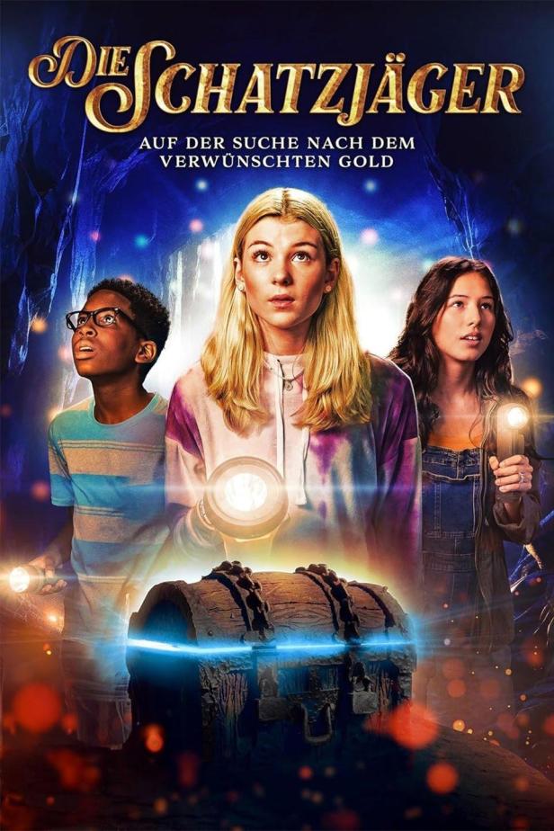 Das Filmplakat für „Die Schatzjäger“ zeigt drei Jugendliche vor einer Schatztruhe in einer Höhle.