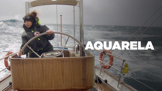 Eine Frau steuert ein Segelboot auf stürmischer See.