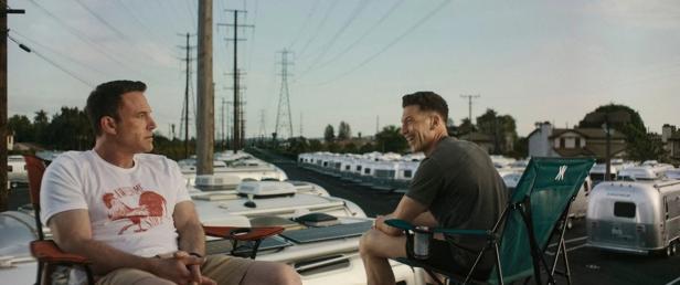 Ben Affleck und Jon Bernthal sitzen auf Campingstühlen inmitten von Wohnwagen.
