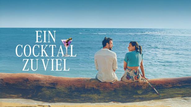 Ein Paar sitzt am Strand auf einem Baumstamm mit Blick auf das Meer.