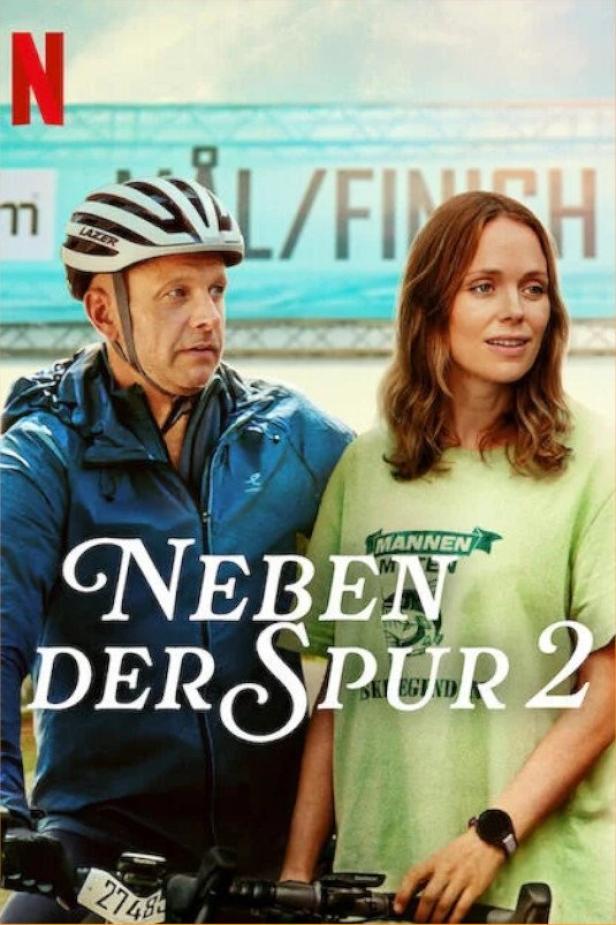 Das Filmplakat für „Neben der Spur 2“ zeigt einen Mann mit Fahrradhelm und eine Frau vor einer Ziellinie.