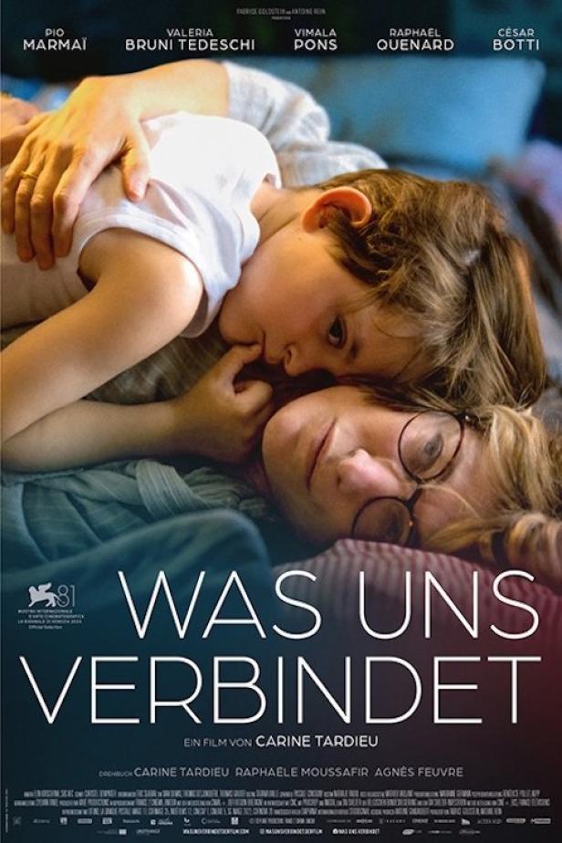 Das Filmplakat für „Was uns verbindet“ zeigt eine Mutter und ihr Kind, die eng aneinander gekuschelt liegen.