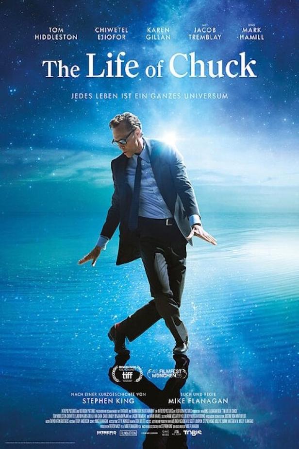 Das Filmplakat für „The Life of Chuck“ zeigt Tom Hiddleston auf einer spiegelglatten Wasseroberfläche.