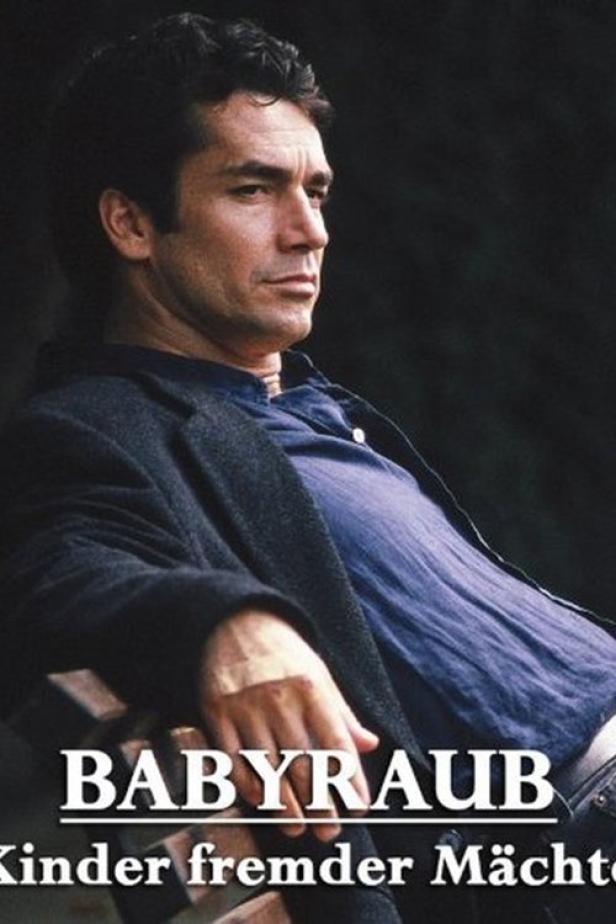 Ein Mann sitzt auf einer Bank, vermutlich eine Szene aus dem Film „Babyraub – Kinder fremder Mächte“.