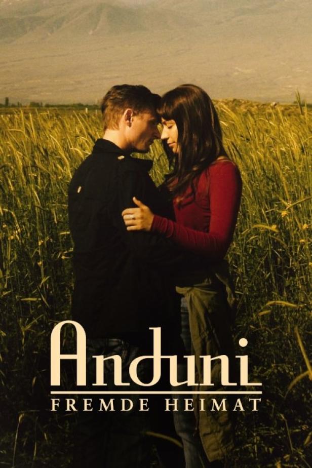 Ein Paar umarmt sich vor einer ländlichen Kulisse, möglicherweise ein Filmposter für „Anduni: Fremde Heimat“.