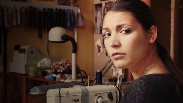 Eine junge Frau sitzt an einer Nähmaschine der Marke Pfaff.