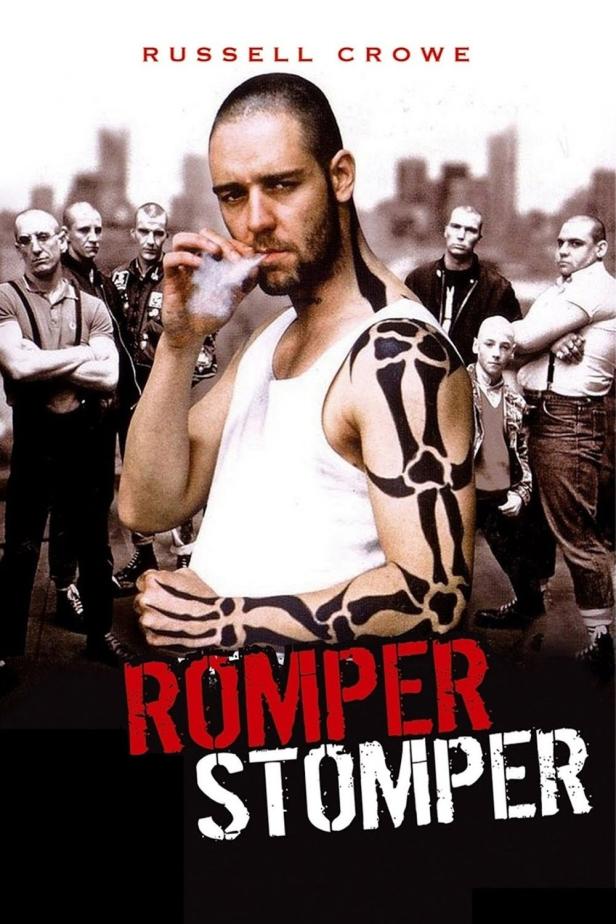 Das Filmplakat für „Romper Stomper“ zeigt Russell Crowe mit Tätowierungen und einer Zigarette, umgeben von anderen Männern.