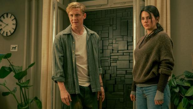 Ein Mann und eine Frau stehen in einem Raum mit einer ungewöhnlichen Wandgestaltung.