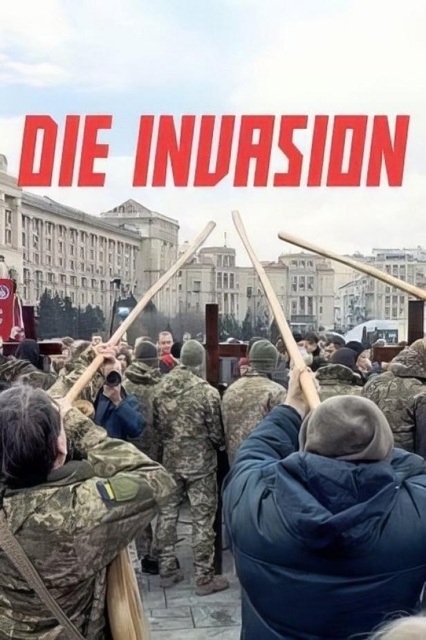 Menschen demonstrieren mit Holzkreuzen und dem Schriftzug „Die Invasion“ im Hintergrund.