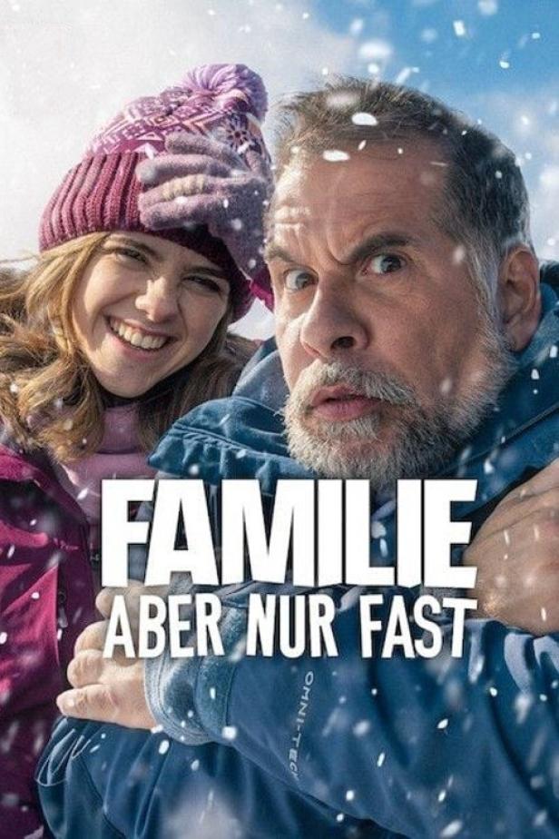 Ein Mann und eine junge Frau umarmen sich im Schnee; Filmposter für „Familie Aber Nur Fast“.