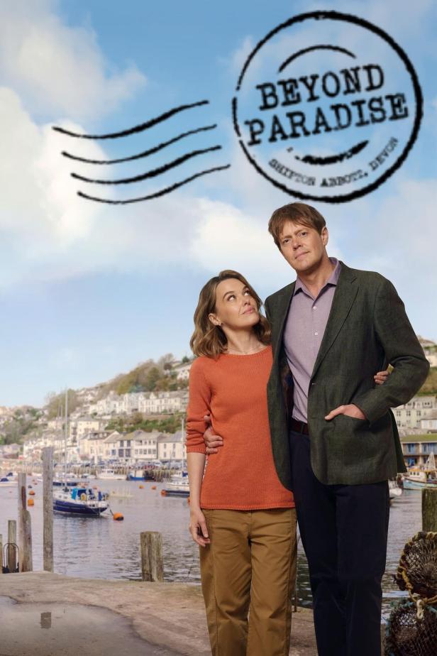 Ein Mann und eine Frau stehen vor der Küstenkulisse der Fernsehserie „Beyond Paradise“.