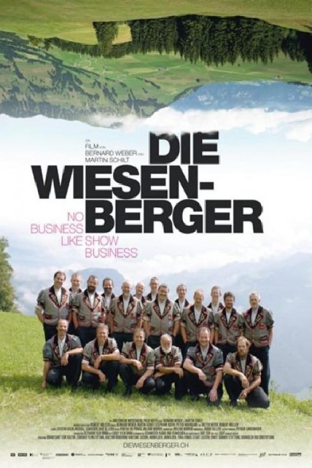 Das Filmplakat für „Die Wiesenberger“ zeigt eine Gruppe Männer in Trachten vor einer Bergkulisse.